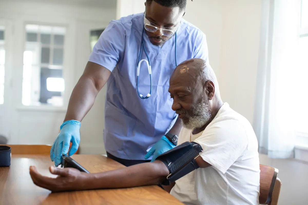 A male nurse checking the vitals of an elderly patient